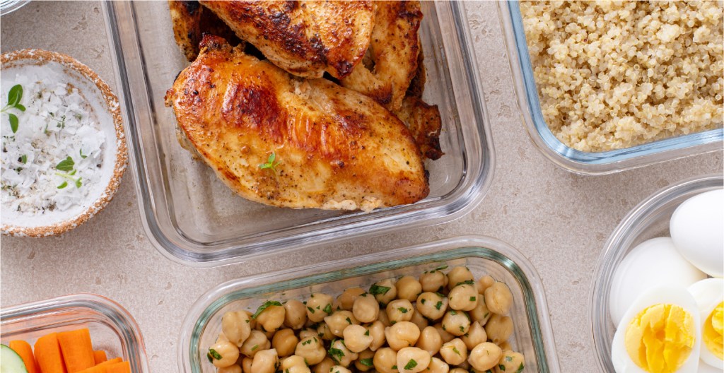 Chicken, quinoa, chick peas, boiled eggs, and vegetables in in glass dishes