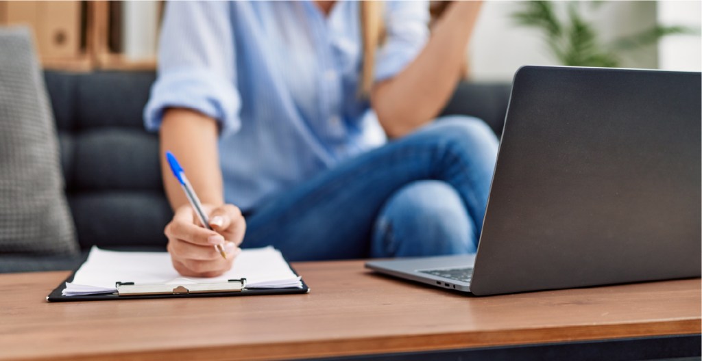 A person looking at a laptop computer taking notes
